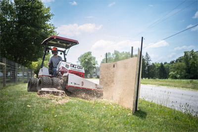Ventrac Stump Grinding - A Ventrac 4520 removing a stump near the road with a barrier set up.