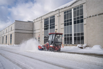 Ventrac Broom - Ventrac Broom clearing light snow from a sidewalk in front of a commercial building. This powerful attachment quickly sweeps away snow, preventing slips and trips and keeping walkways unobstructed. Perfect for efficient sidewalk snow removal with unmatched precision and ease.