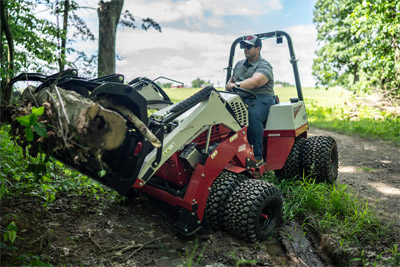 Ventrac Loader - Ventrac tractor with the KM500 Loader hauling brush from rugged, uneven trails. The FlexFrame design keeps the tractor stable and adaptable, making it easy to navigate tough terrain while handling heavy loads. Built for hard-to-reach jobs with unmatched versatility and performance.