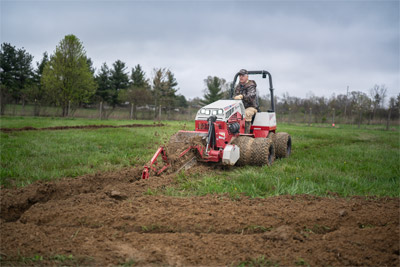 Ventrac Trencher - Easily fix drainage problems with the Ventrac KY400 Trencher, shown here digging precise lines to install french drains in a horse pasture. This efficient solution ensures effective drainage while preserving the turf for year-round use by animals.