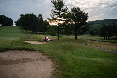 Ventrac Contour Mower - The Ventrac Contour Mower effortlessly maneuvers around sand traps and bunkers on a golf course, featuring an 83-inch working width and independent floating decks. Its design allows up to 40 degrees of motion for precise mowing and even cutting on varied terrain.