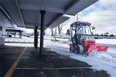 Ventrac V-Blade - The Ventrac 4520 with a V-Blade works in a tight space beneath a building overhang, clearing snow where larger equipment cannot go. Its compact size allows the operator to work close to walls and structures.