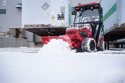 Ventrac V-Blade - The Ventrac 4520 with a V-Blade clears snow from a loading dock, ensuring trucks can access the area without delay. Its compact size allows it to work close to docks and tight spaces, while the powerful blade efficiently moves snow aside.